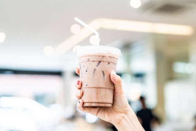 Mão segurando o copo de milkshake de chocolate belga gelado