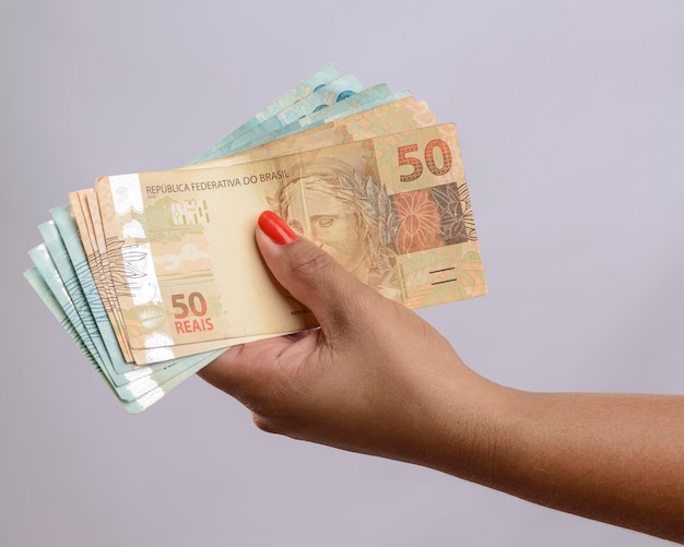 Foto mão segurando o dinheiro seiscentos reais moeda brasileira no fundo branco
