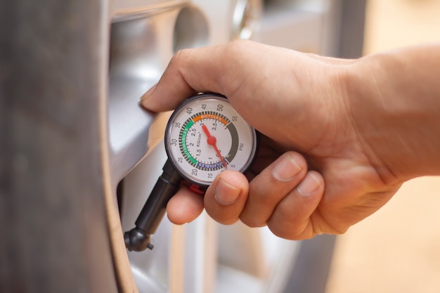 Mão segurando o manômetro para medição de pressão de pneu de carro