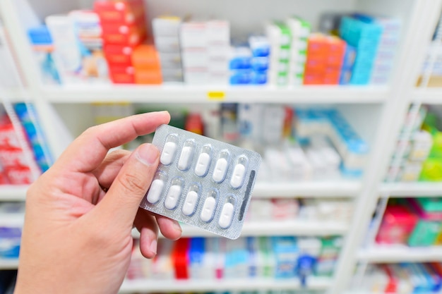 Mão segurando o pacote de medicamento na farmácia Farmácia