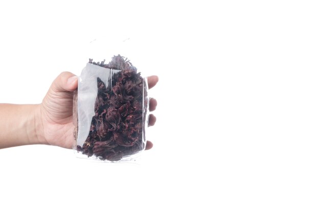 Mão segurando o pacote de roselles vermelhos secos para fazer um chá de ervas