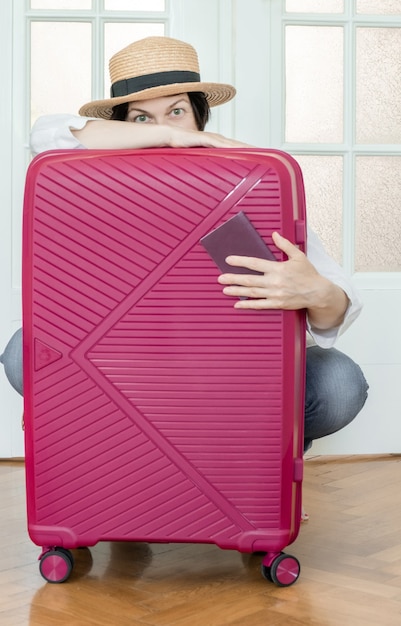 Mão segurando o passaporte romeno no fundo rosa mala e pronta para viajar.