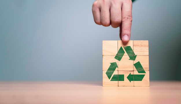 Foto mão segurando o rótulo de reciclagem verde no cubo de bloco de madeira ecológico para salvar a terra e o desenvolvimento sustentável para o sucesso no conceito de crescimento empresarial