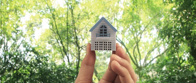 Mão segurando o seguro e a segurança da propriedade do modelo de casa Compre o conceito de casa de aluguel