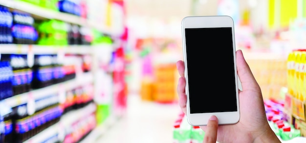 Mão segurando o smartphone com uma tela em branco em um supermercado