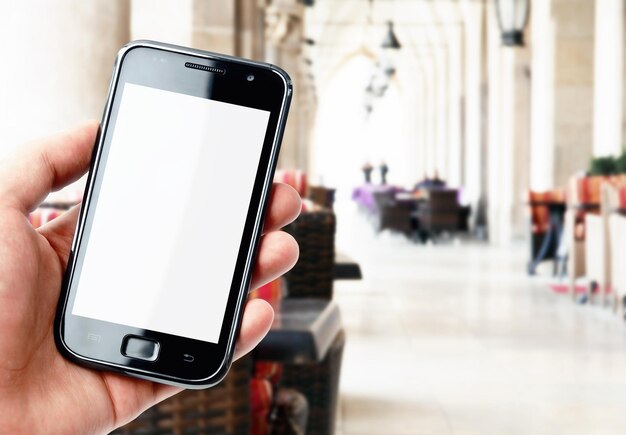 Mão segurando o smartphone no café da cidade