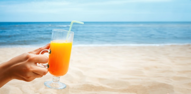 Mão segurando o suco em um copo na paisagem turva