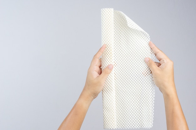 Mão segurando o tapete de borracha antiderrapante branco para banheiro ou piso molhado
