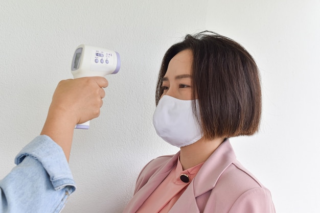 Mão segurando o termômetro infravermelho na testa para verificar a temperatura corporal. conceito de proteção do coronavírus (covid-19).