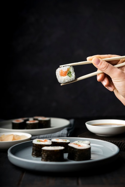 Mão segurando os pauzinhos para rolos de sushi vista frontal