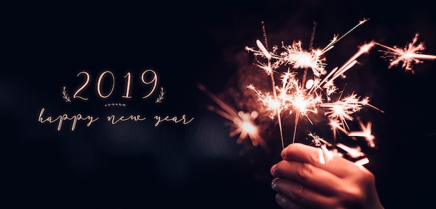 Mão, segurando, queimadura, sparkler, explosão, com, feliz ano novo, 2019, ligado, um, pretas, bokeh, fundo