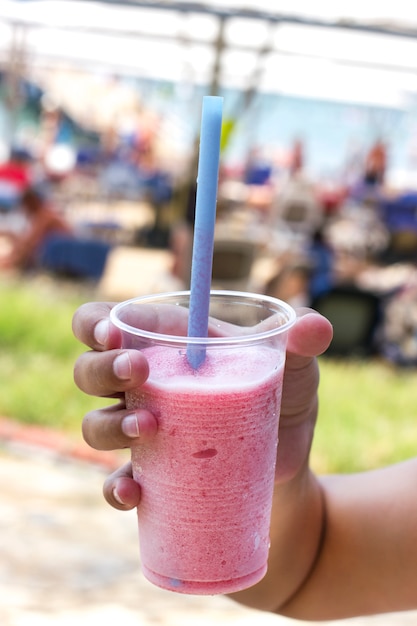 Mão segurando rosa cocktail com gelo picado - morango frappe