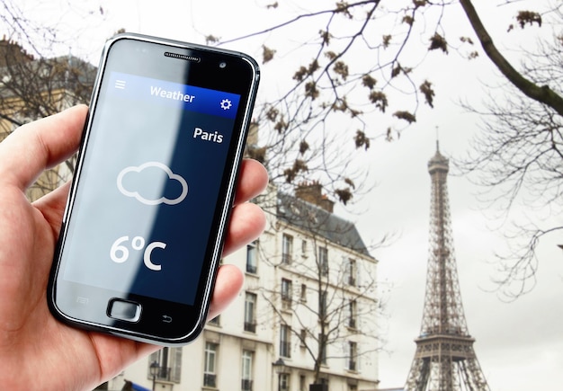 Mão segurando smartphone com clima em Paris