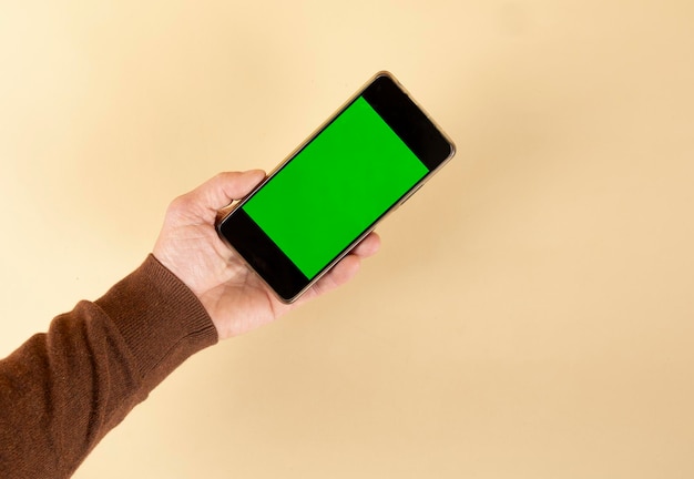 Mão segurando smartphone com tela verde