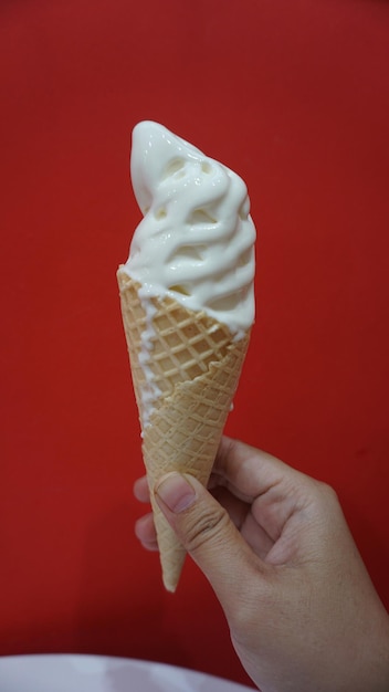 Foto mão segurando sorvete contra parede colorida de pavão