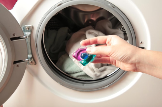 Mão segurando tampas de gel para máquina de lavar Equipamento de lavanderia doméstica Limpeza de roupas de primavera