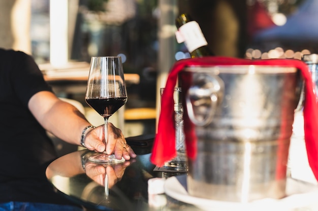 Foto mão segurando um copo de vinho vermelho em um restaurante em uma mesa ao ar livre