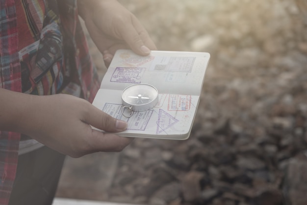 Mão segurando um passaporte da bússola para encontrar destinos de viagem. Estilo vintage.