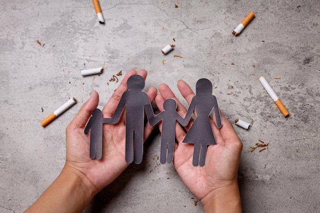 Mão segurando um pedaço de papel da família com cigarros Pare de fumar para sua família
