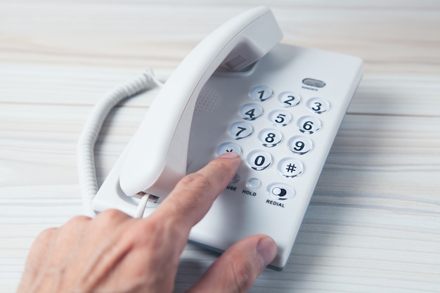 Mão segurando um receptor de telefone residencial