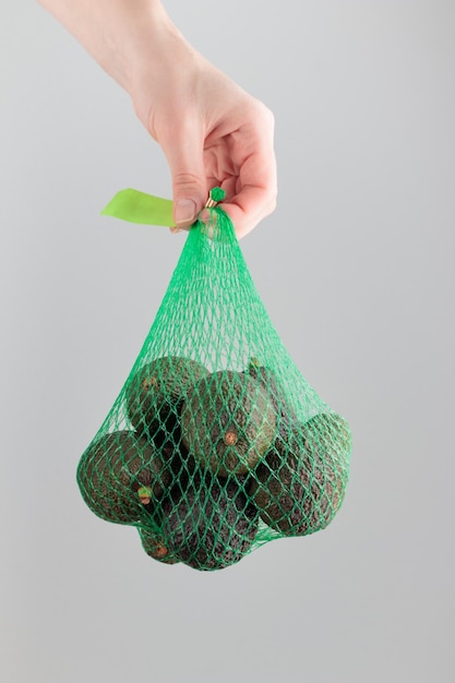 Mão segurando um saco de abacate