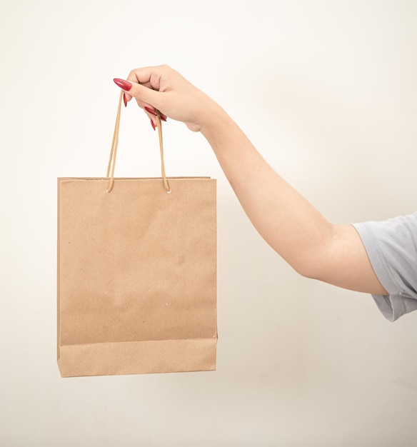 Foto mão segurando um saco de papel de compras contra um fundo isolado branco
