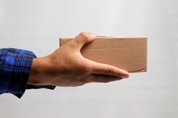 Foto mão segurando uma caixa de papelão contra um fundo cinzento