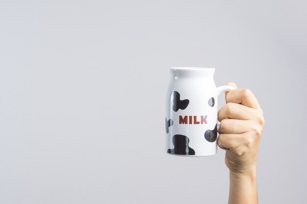 Mão segurando uma caneca com padrão de leite