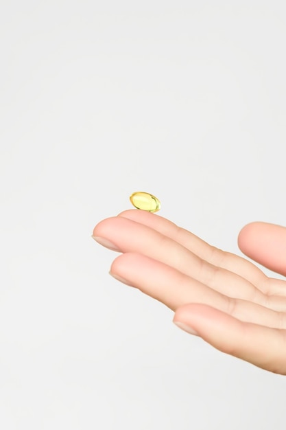 mão segurando uma cápsula de vitamina tomando vitaminas e suplementos nutricionais para a saúde feminina