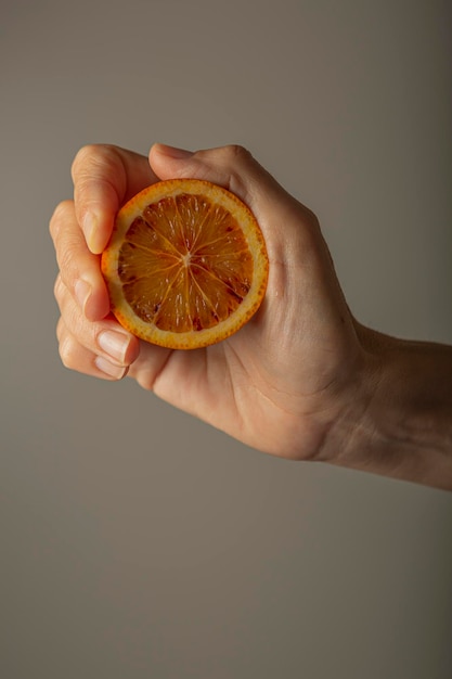 Mão segurando uma fatia circular de laranja contra a luz