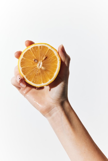 Mão segurando uma fatia de laranja na frente de um fundo branco