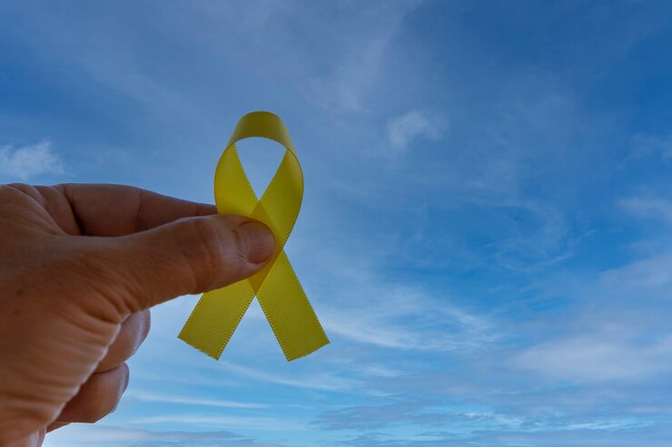 Foto mão segurando uma fita amarela com fundo de céu azul. setembro amarelo campanha de prevenção de suicídio
