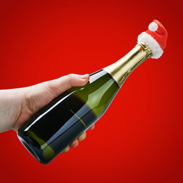 Mão segurando uma garrafa de champanhe em uma decoração de natal santa