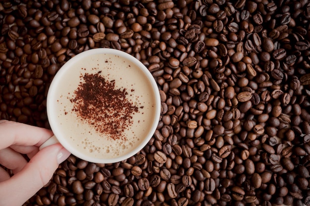 Mão segurando uma xícara de café branca