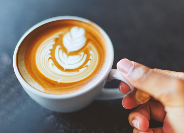 Mão segurando uma xícara de café com leite Dia internacional do café