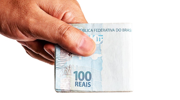 Foto mão segurando várias notas de cem reais do brasil em fundo branco isolado projeto bancário ou conceito de lucro financeiro