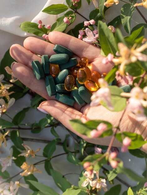 mão segurando vitaminas e minerais em flores