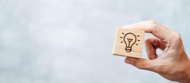 Mão segure o bloco de lâmpada com criatividade de inovação de estratégia de ideias de negócios aprendendo brainstorming e conceito de sucesso