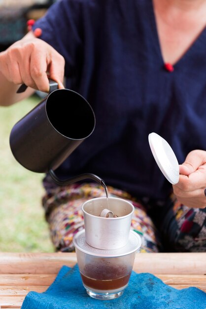 Mão servindo água quente para o café pingar