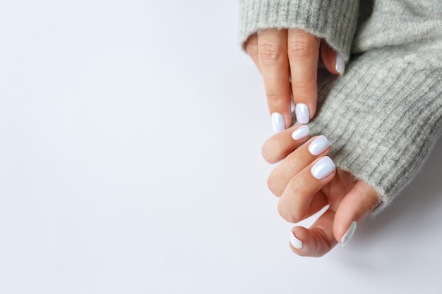 Mão sobre uma superfície branca e bela manicure pérola de perto