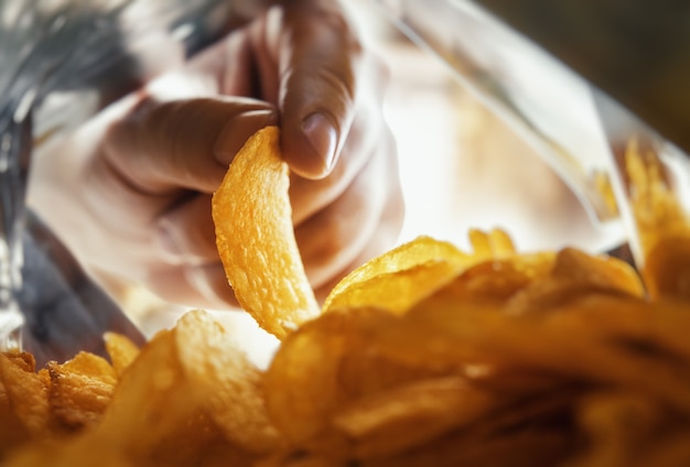 Mão tira batatas fritas dentro da embalagem