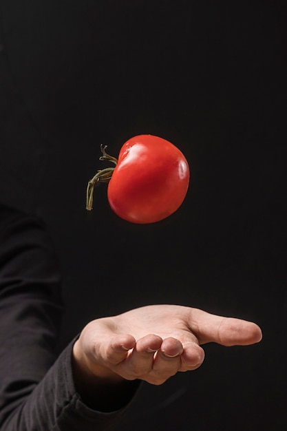 Foto mão vomitando tomate no ar