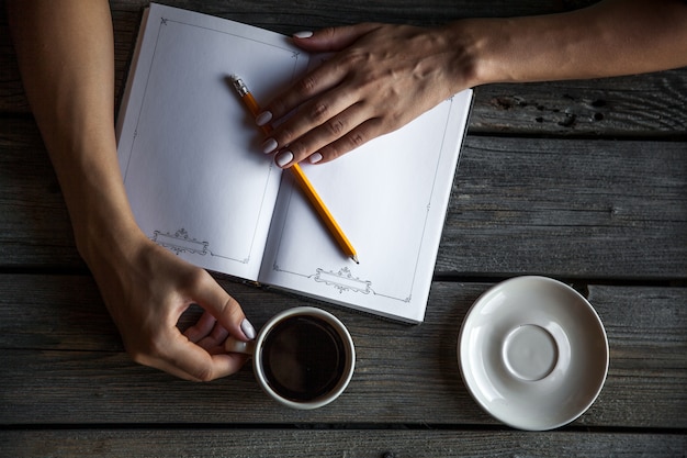 Mãos abertas Catálogo em branco, revistas, livro na mesa de madeira com café