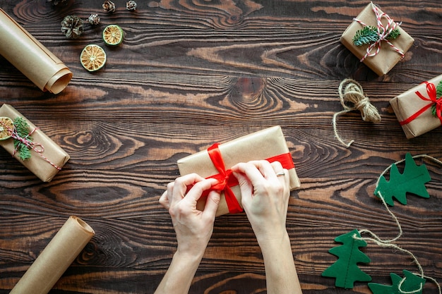 Mãos amarrando um laço vermelho em uma caixa de presente de Natal