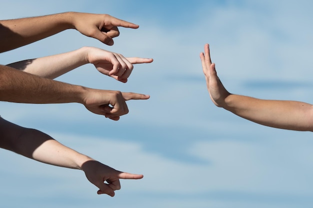 Mãos apontando para uma pessoa fazendo o gesto de parada com a palma da mão Acusação e conceito de culpa