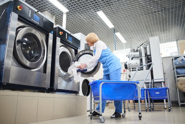Foto mãos carregando roupa na máquina de lavar na tinturaria