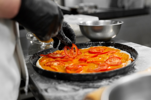 mãos coloca tomates na massa