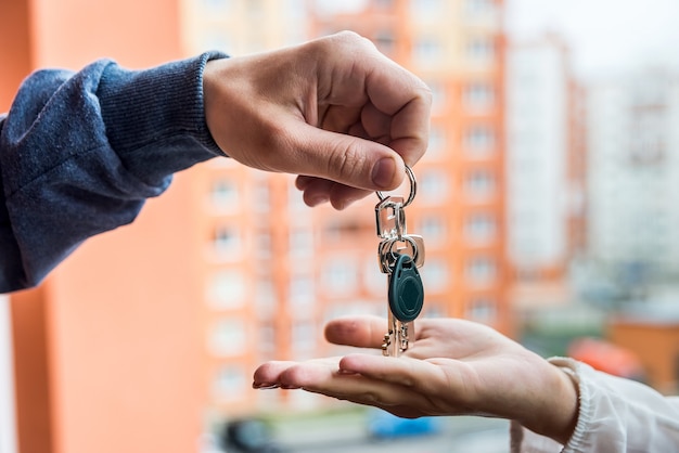 Mãos com as chaves do novo apartamento e um monte de dólares