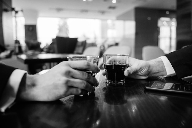 Mãos com copos de bebida no bar