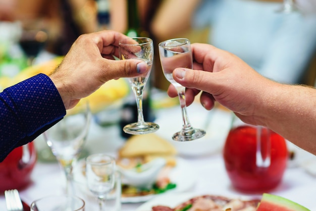 Mãos com copos de vodka em um evento